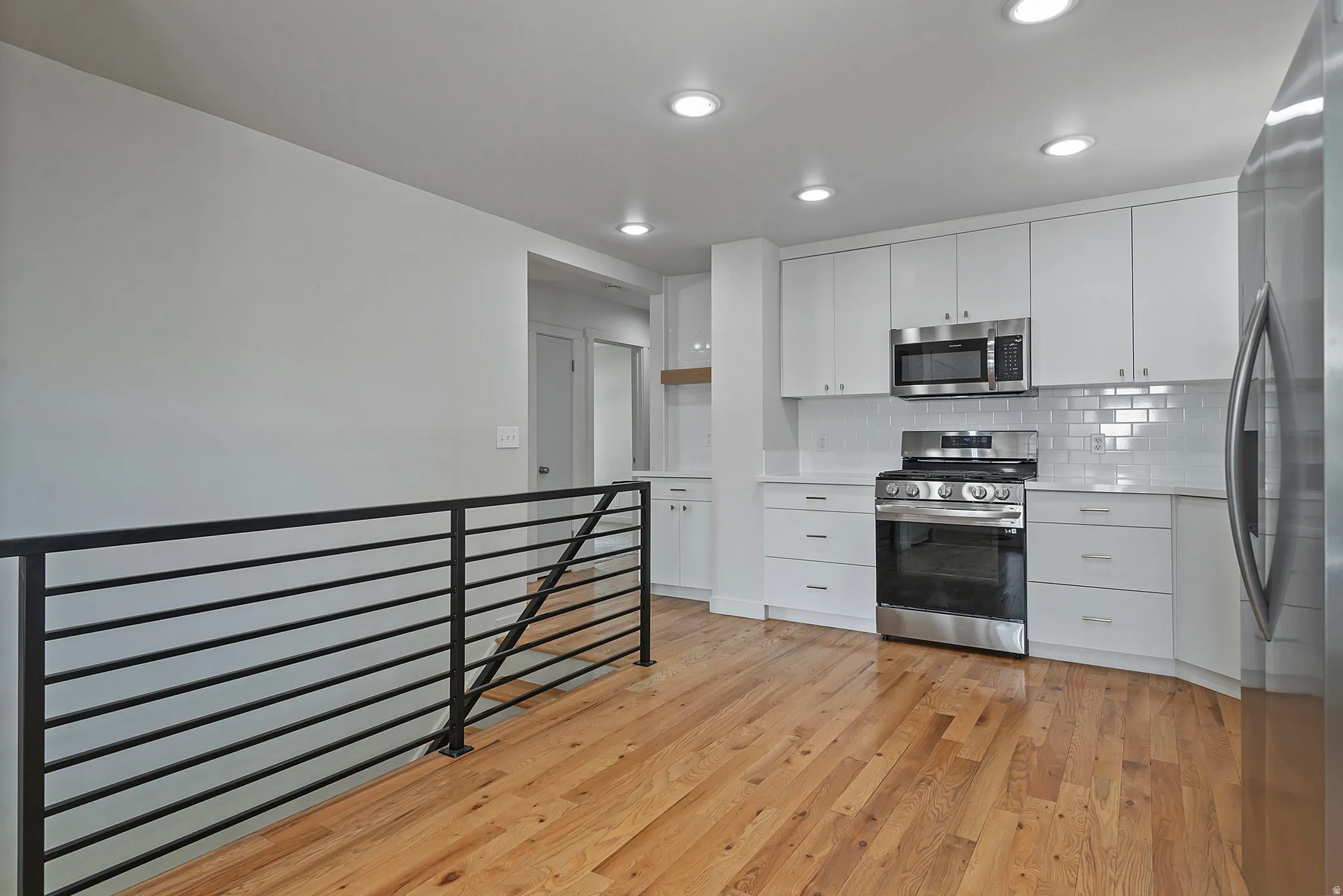Modern kitchen featuring white cabinetry, subway tile backsplash, stainless steel appliances, and a gas range