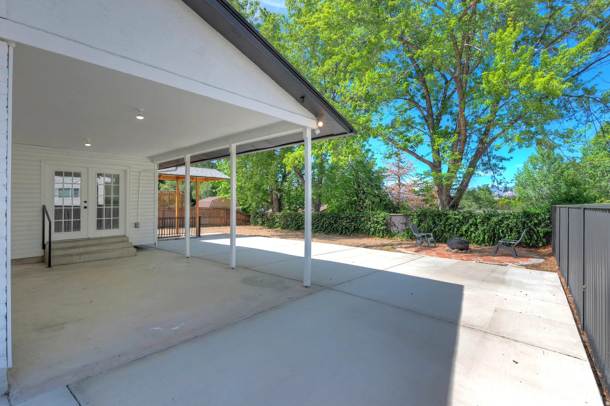Covered patio with recessed lighting and concrete flooring, featuring French doors with transom windows