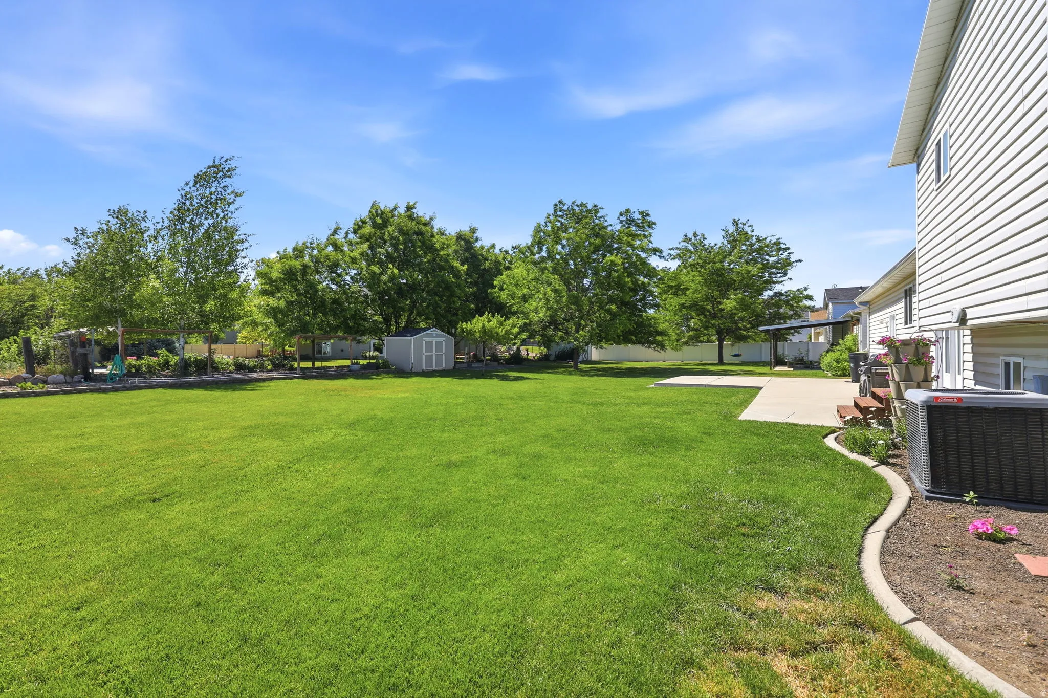 Expansive green lawn with mature trees and a detached storage shed