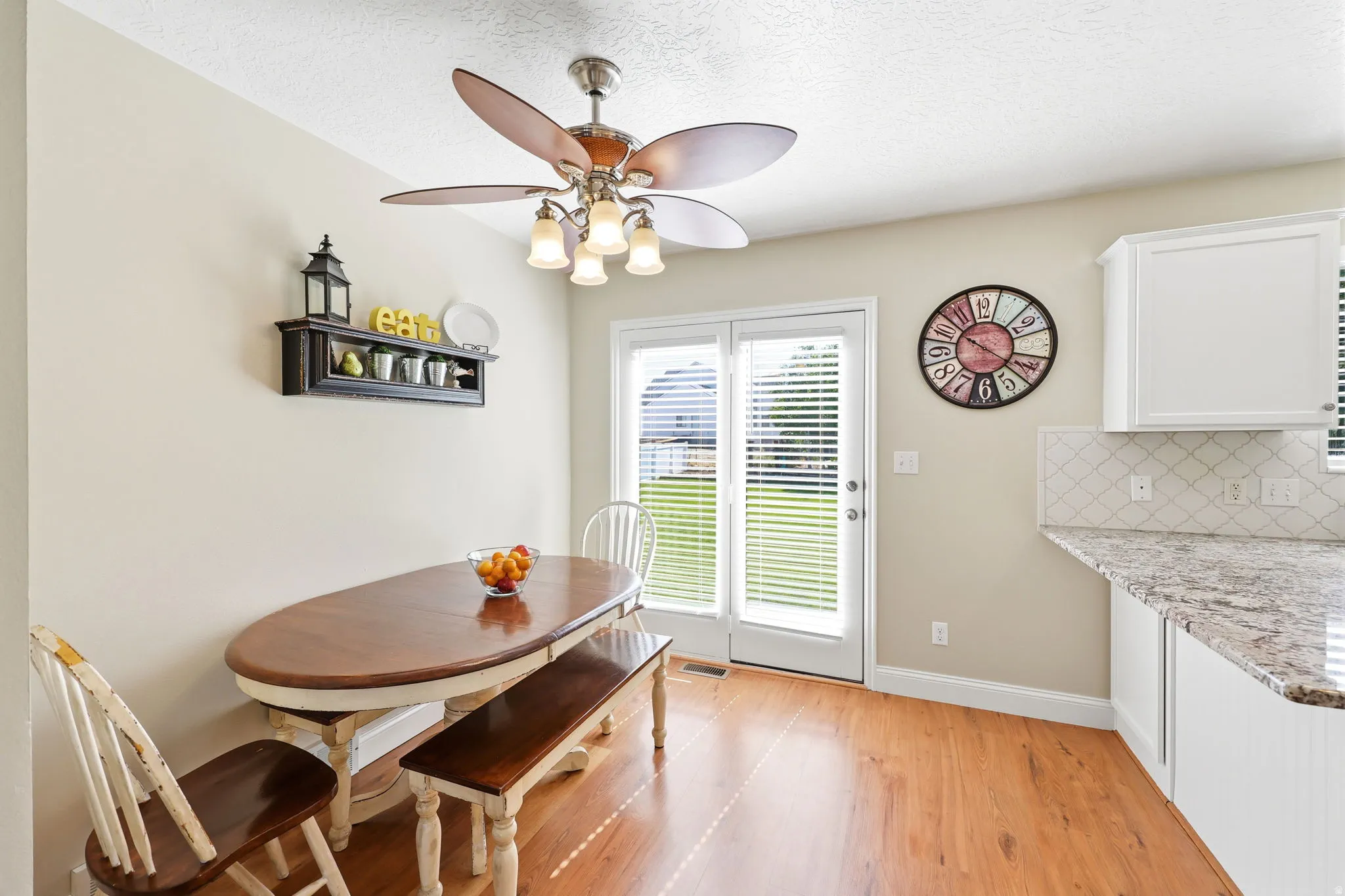 Dining area featuring wood-finish flooring, a ceiling fan with integrated lighting, and direct access to the exterior through double French doors
