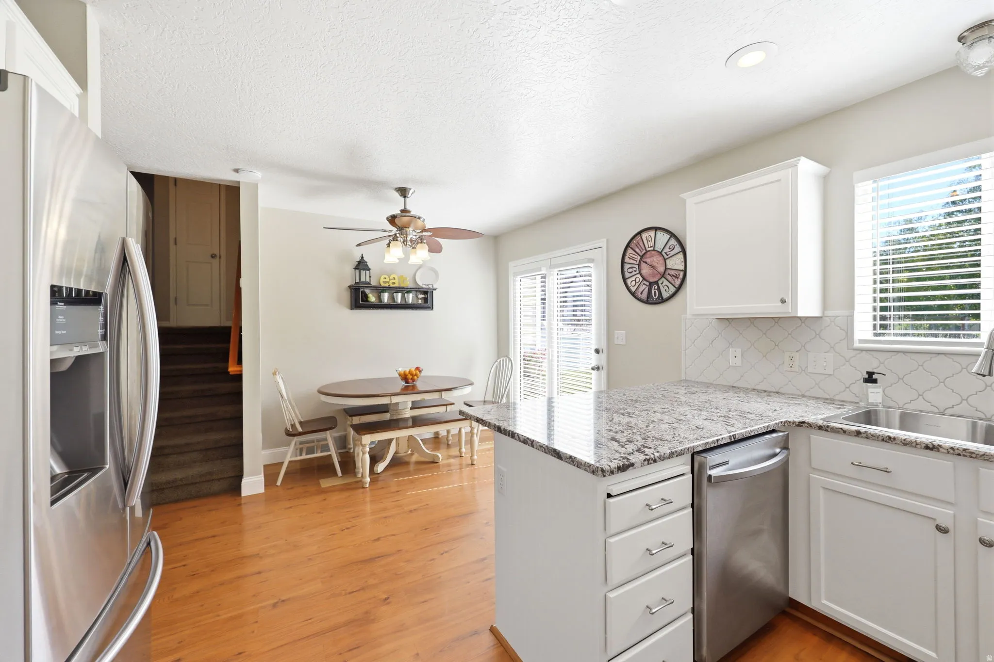 Kitchen featuring granite countertops, white cabinetry, stainless steel appliances, wood-finish flooring, and a sliding glass door