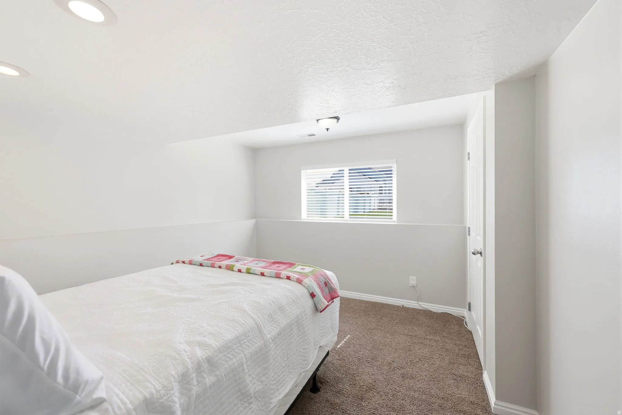 Light-toned room featuring recessed ceiling lighting, a window with horizontal blinds, neutral wall paint, and brown carpet flooring
