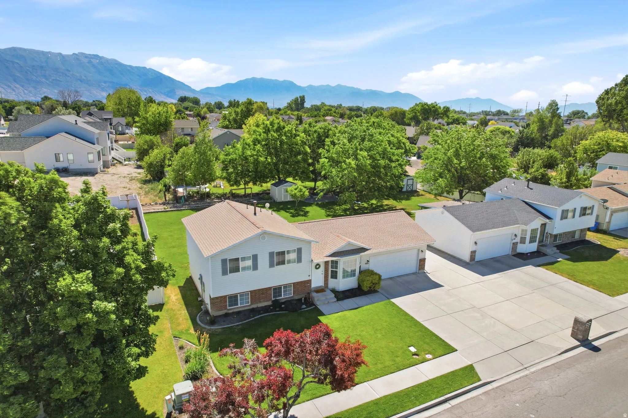 Split-level residence featuring a two-car garage, established front landscaping, and a spacious rear yard