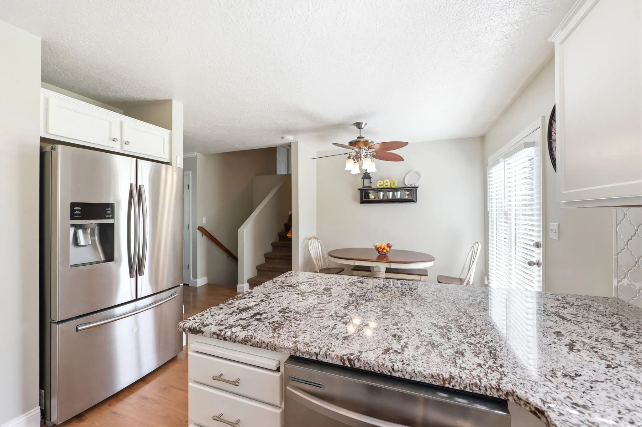 Kitchen featuring stone countertops, white cabinetry, stainless steel appliances, and a mosaic tile backsplash