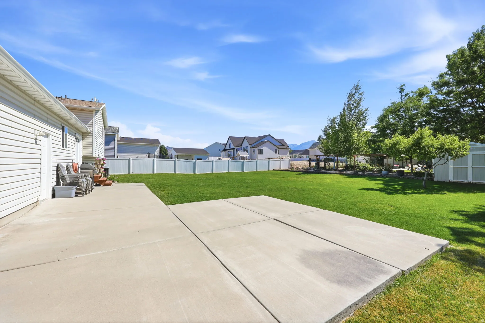 Expansive concrete patio area extending onto a large, flat lawn