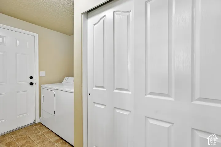 Utility area with panel doors, neutral wall paint, and ceramic tile flooring