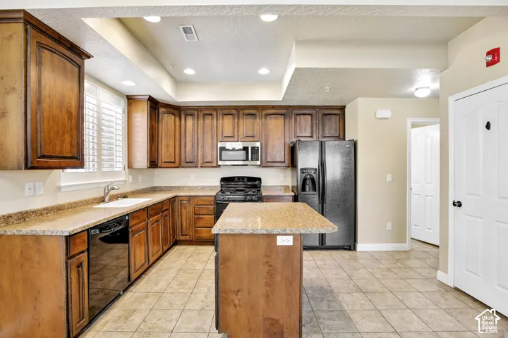 Kitchen featuring wood cabinetry, granite-finish countertops, and black appliances