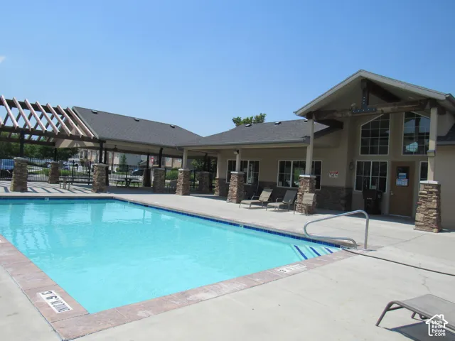 Outdoor swimming pool with concrete surround, adjacent to a stucco building featuring Gym and bathrooms