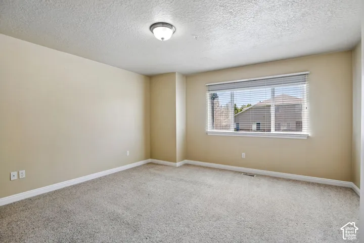 Bedroom featuring neutral-toned walls, textured carpet flooring, and a flush-mount ceiling light