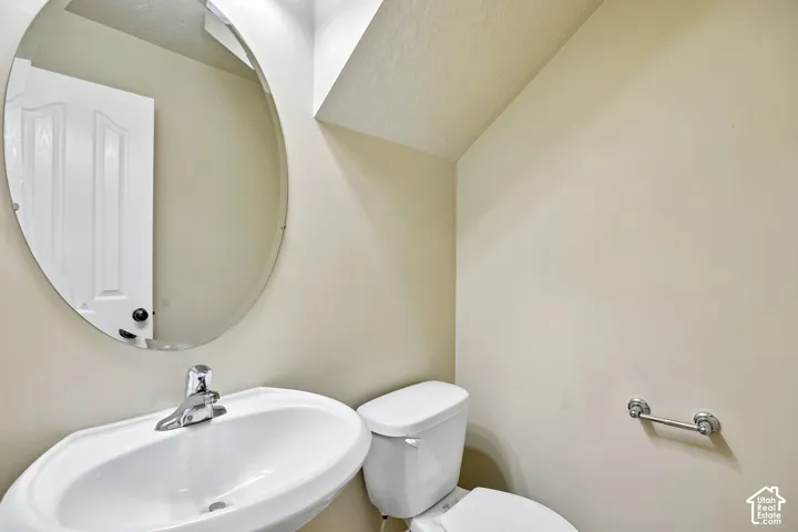 Pedestal sink with chrome faucet, oval mirror, and white toilet