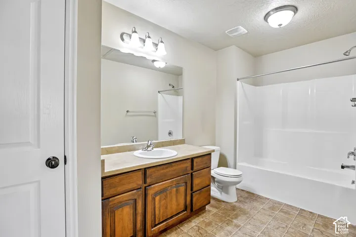 Bathroom featuring a wood-finish vanity with a single basin sink, a light-toned countertop, and a vanity mirror