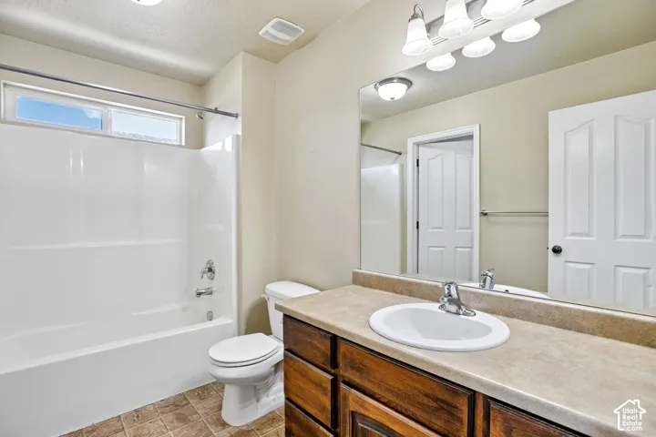 Primary attached bathroom vanity featuring a single basin sink, laminate countertop, and wood-finish cabinetry