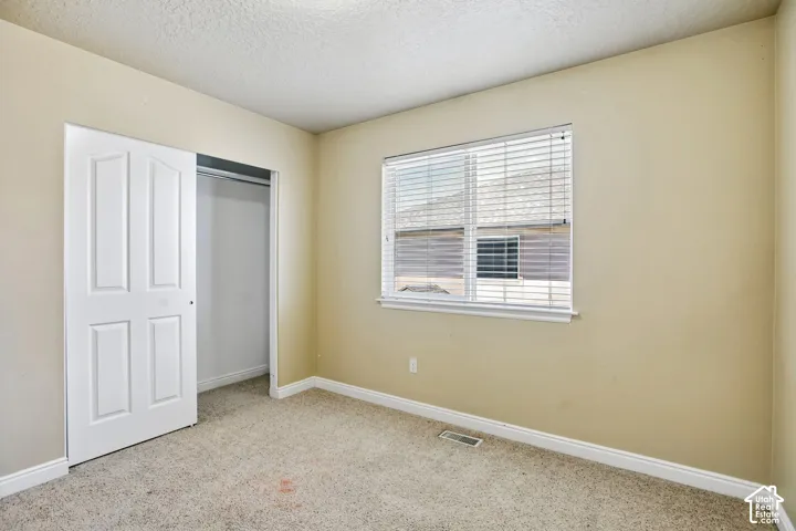 Carpeted room with a double-pane window featuring horizontal blinds