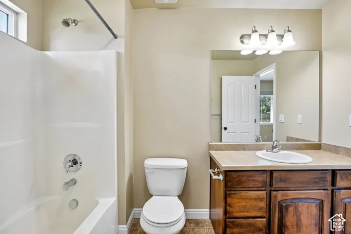 Primary attached bathroom featuring a white shower-over-tub combination with chrome fixtures, a toilet, and a vanity with a light-colored countertop