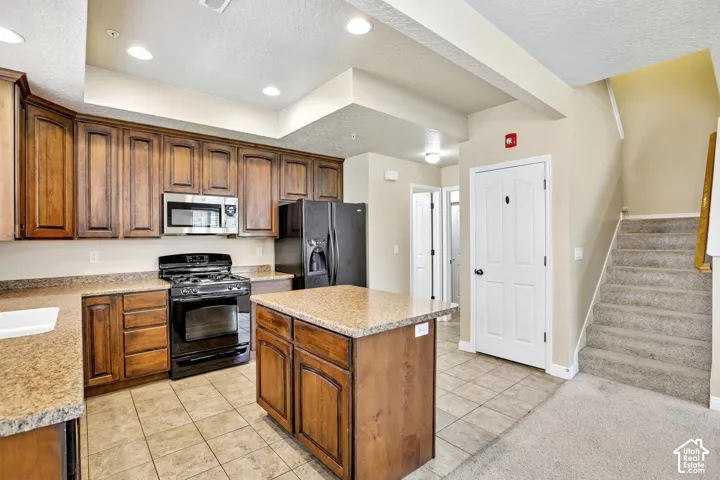 Kitchen featuring wood cabinetry, stone-finish countertops, and black appliances