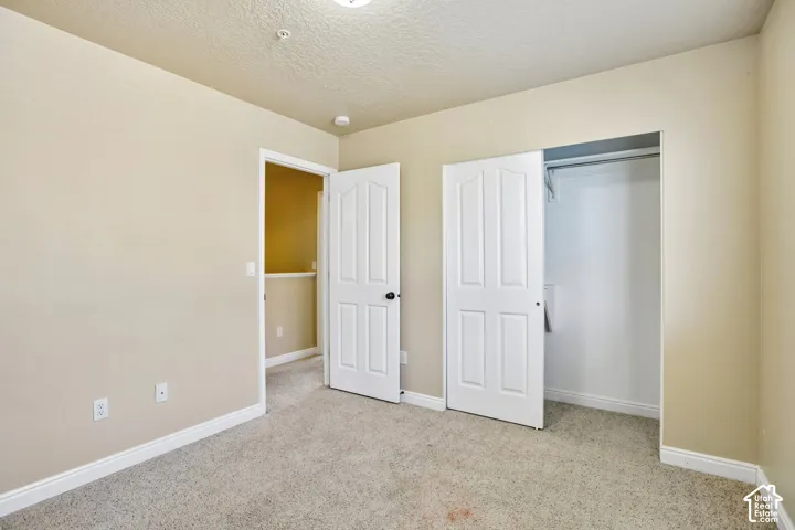 Interior room featuring neutral-toned walls, textured ceiling, and light-colored carpeting