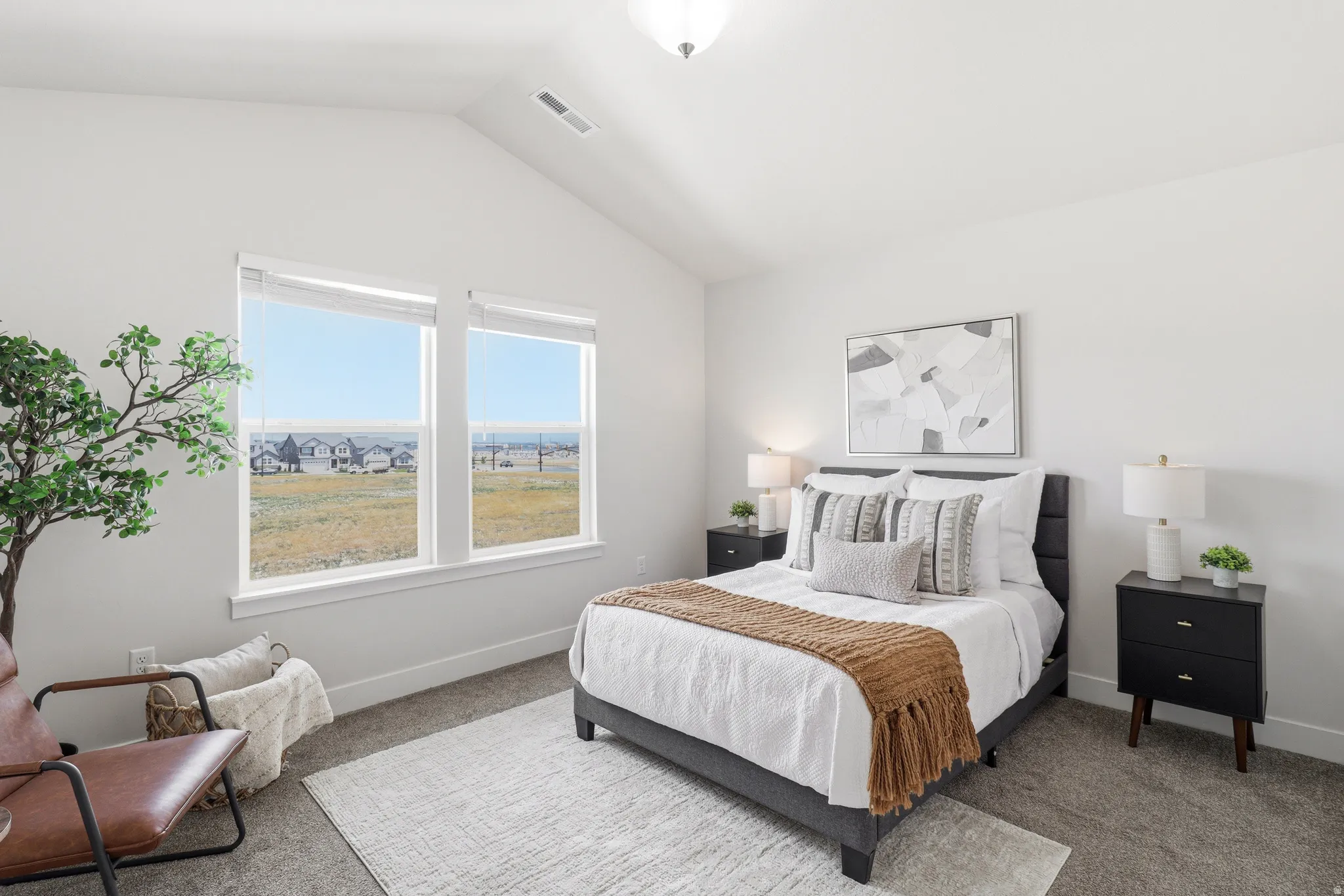 Vaulted ceilings enhance this bright room, featuring large windows with distant landscape views