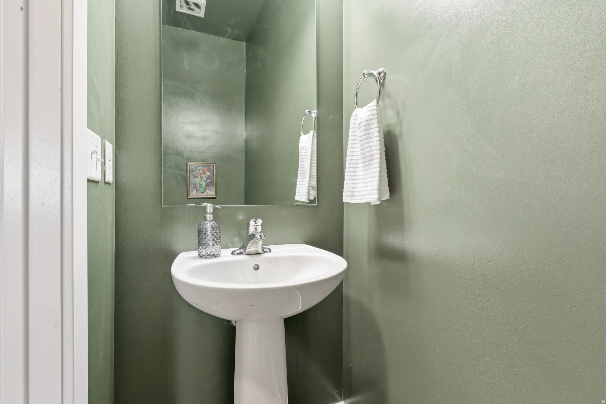 Pedestal sink with chrome-finish faucet and wall-mounted mirror