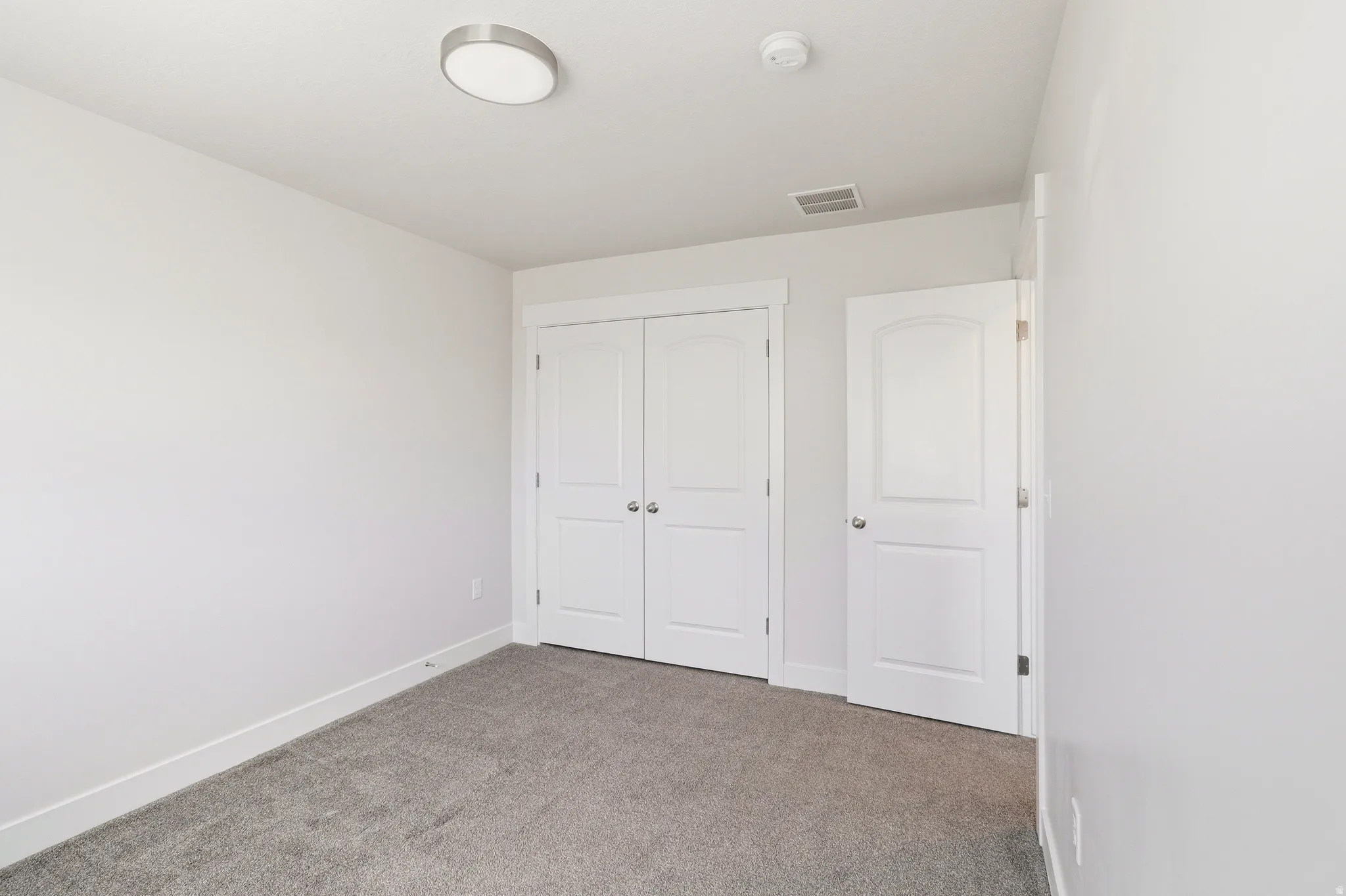 Neutral-toned walls and grey carpeting complement a closet with double panel doors