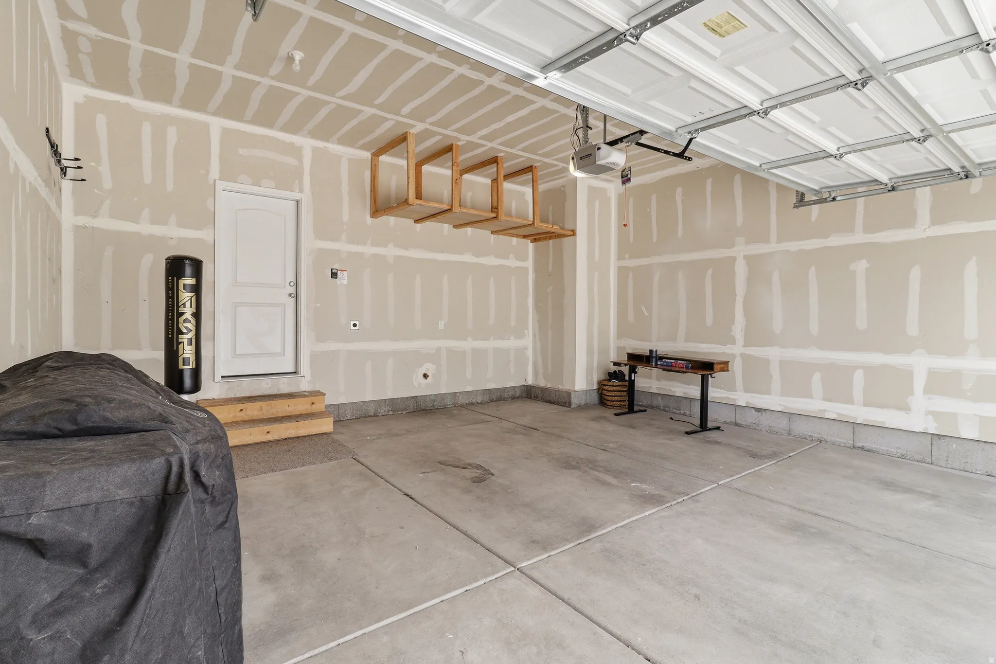 Spacious garage with concrete flooring, automatic garage door opener, and a side entry door
