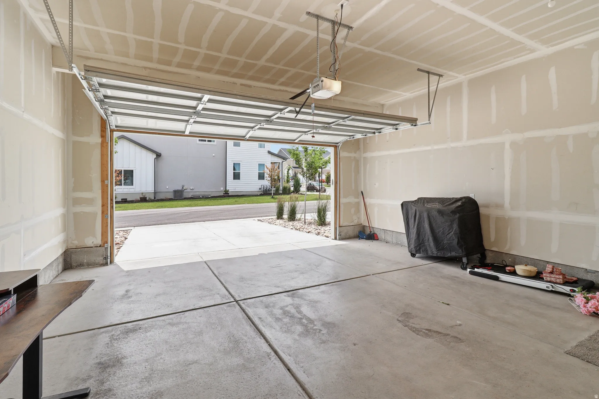 Two-car garage featuring a concrete floor, automatic garage door opener, and unfinished drywall walls