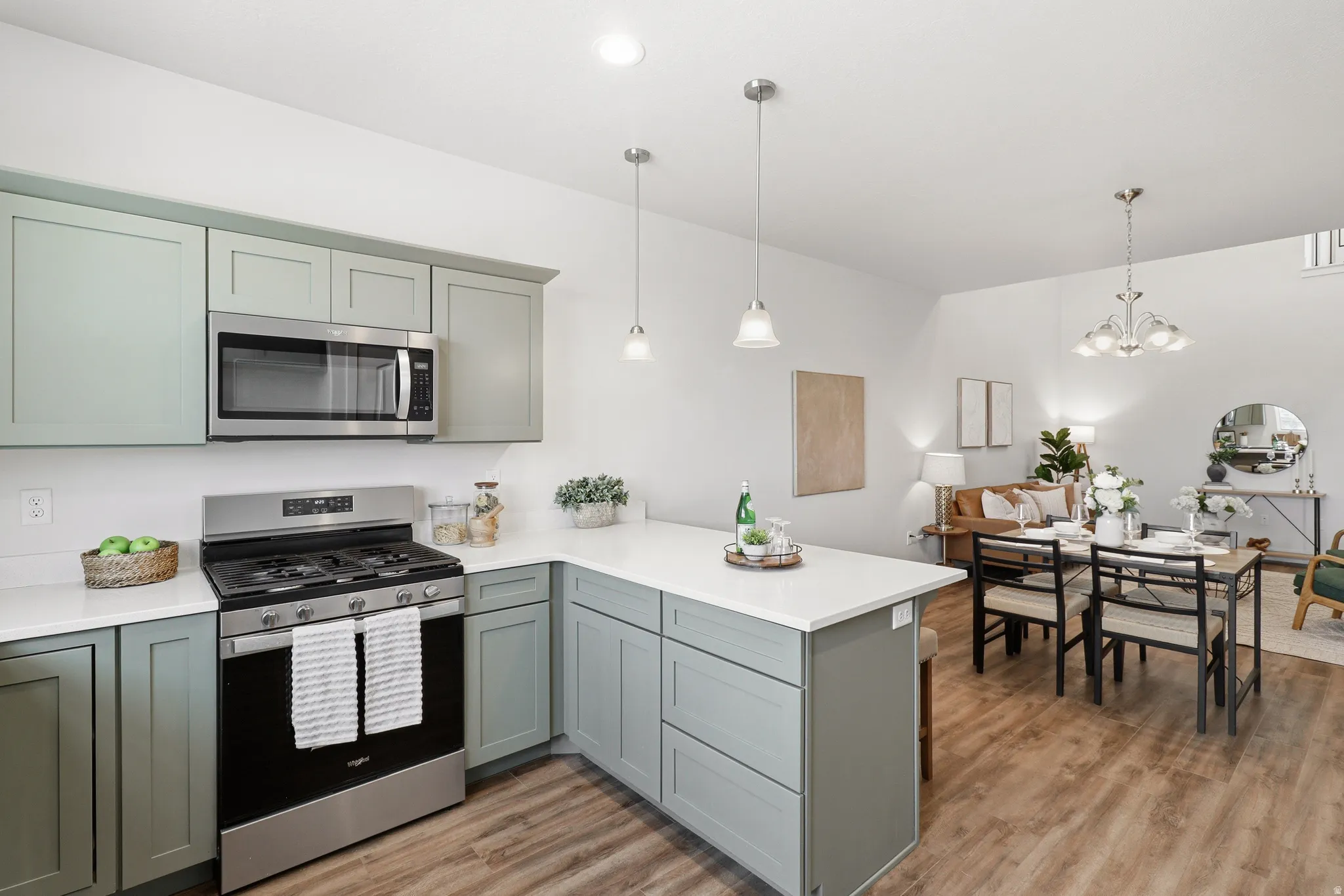 Contemporary kitchen featuring light green cabinetry, white countertops, and stainless steel appliances