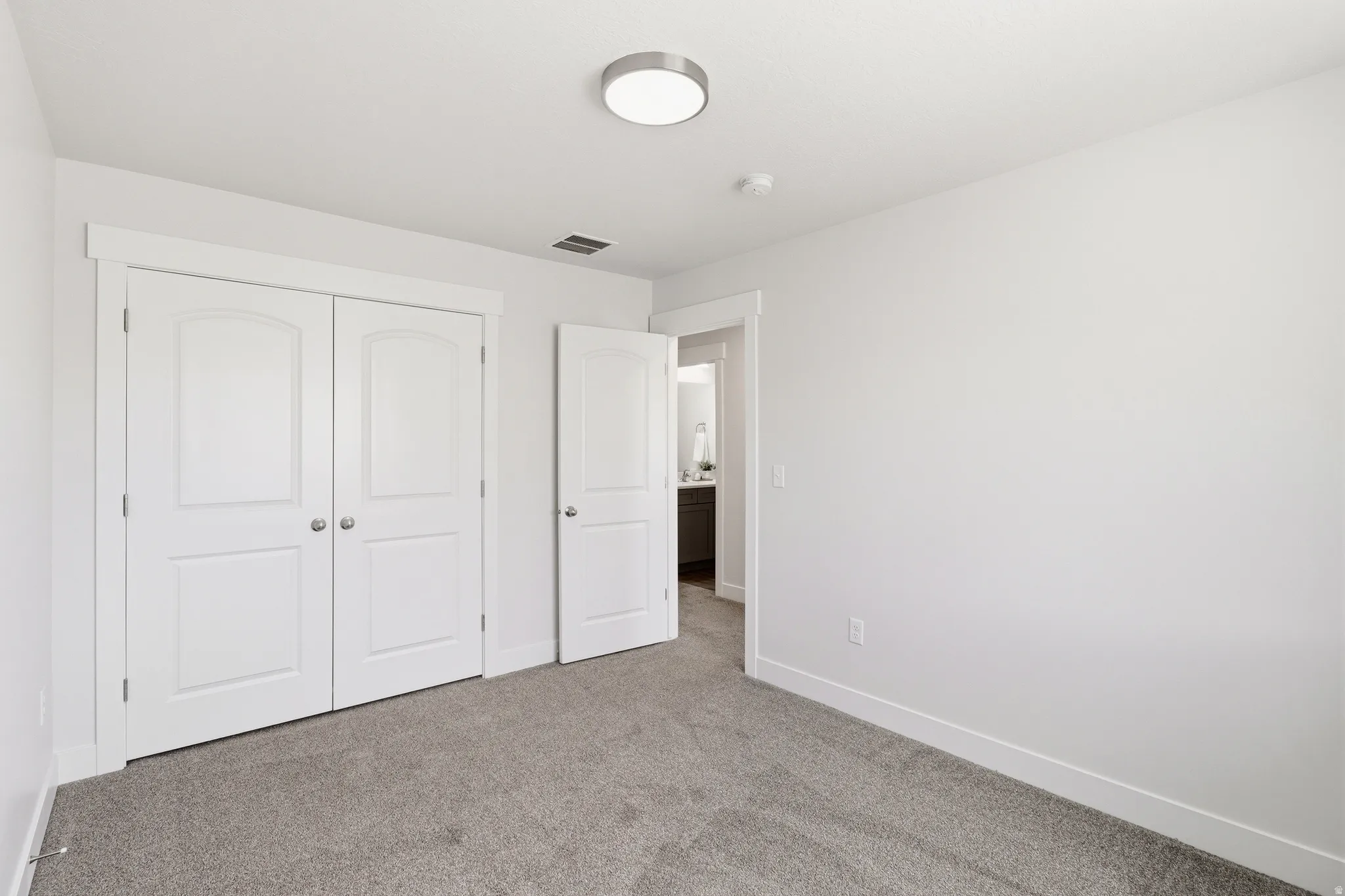 Carpeted room featuring white walls, white trim, and a white ceiling with a flush-mount light fixture
