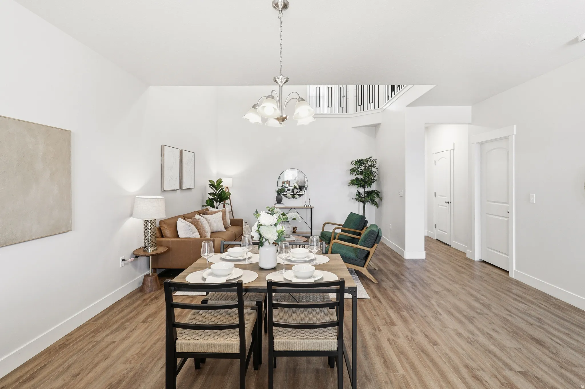 Open-concept living space featuring wood-finish flooring, white walls, and a contemporary chandelier