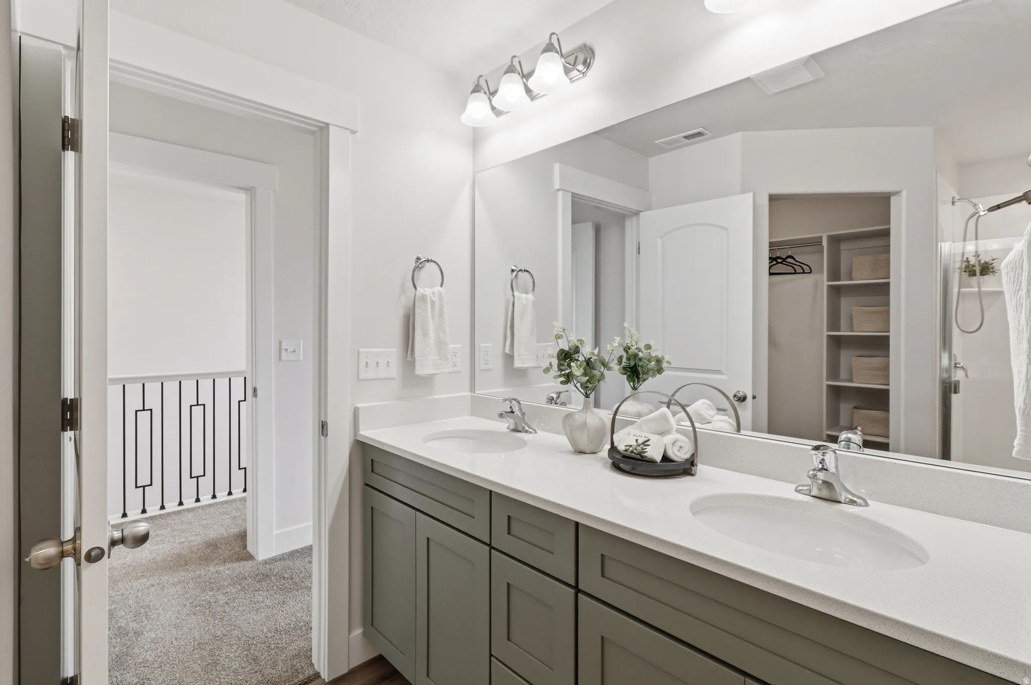 Dual undermount sinks set in a light-toned countertop, complemented by a gray vanity with chrome hardware