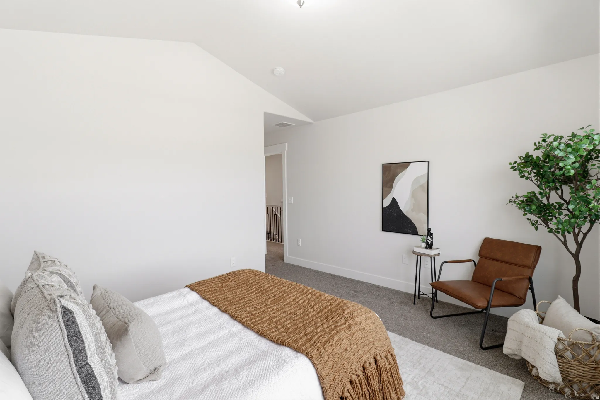 Neutral-toned bedroom with sloped ceiling, light gray carpeting, and white baseboards