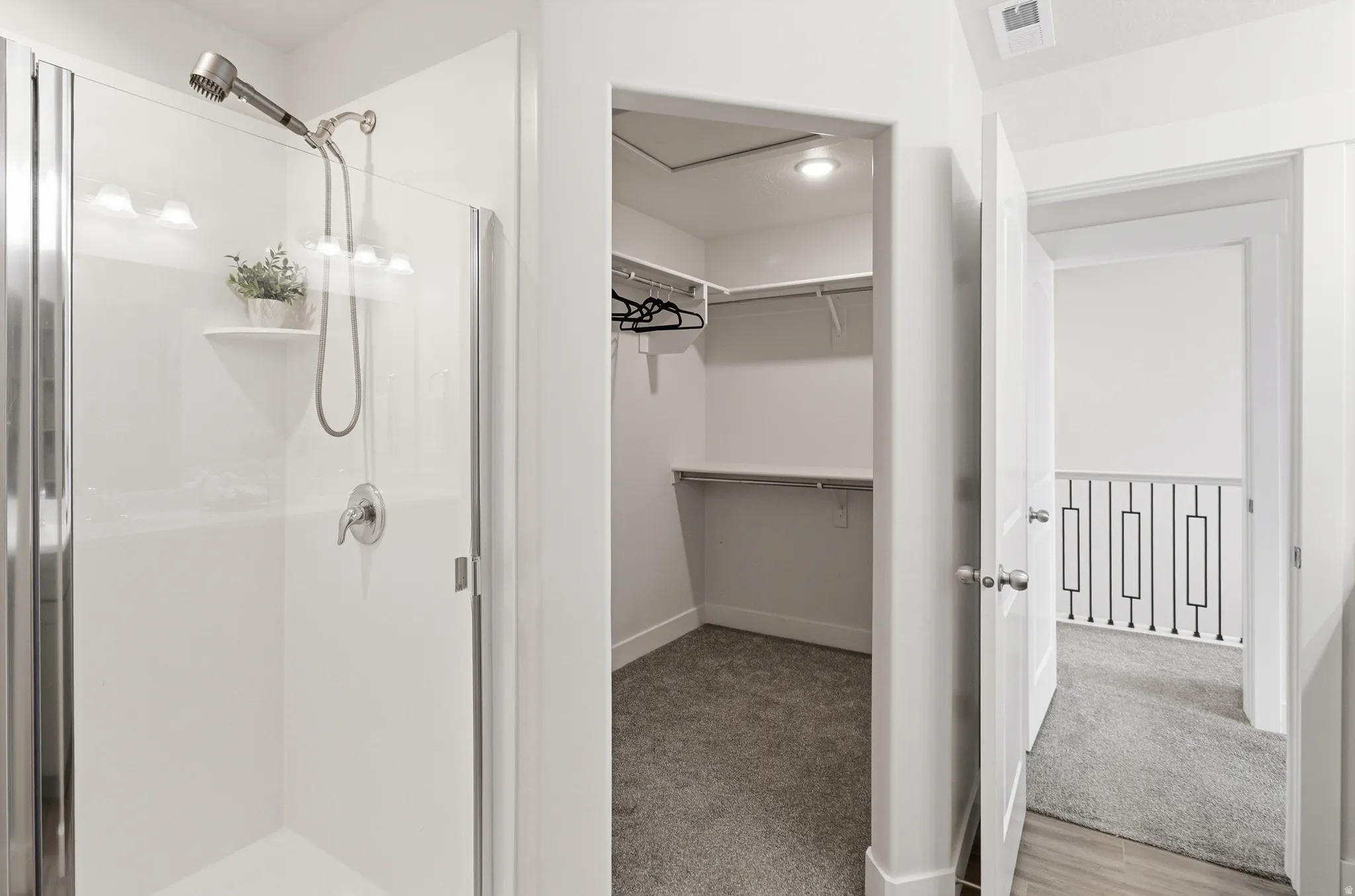 Enclosed shower stall with a brushed nickel showerhead and control