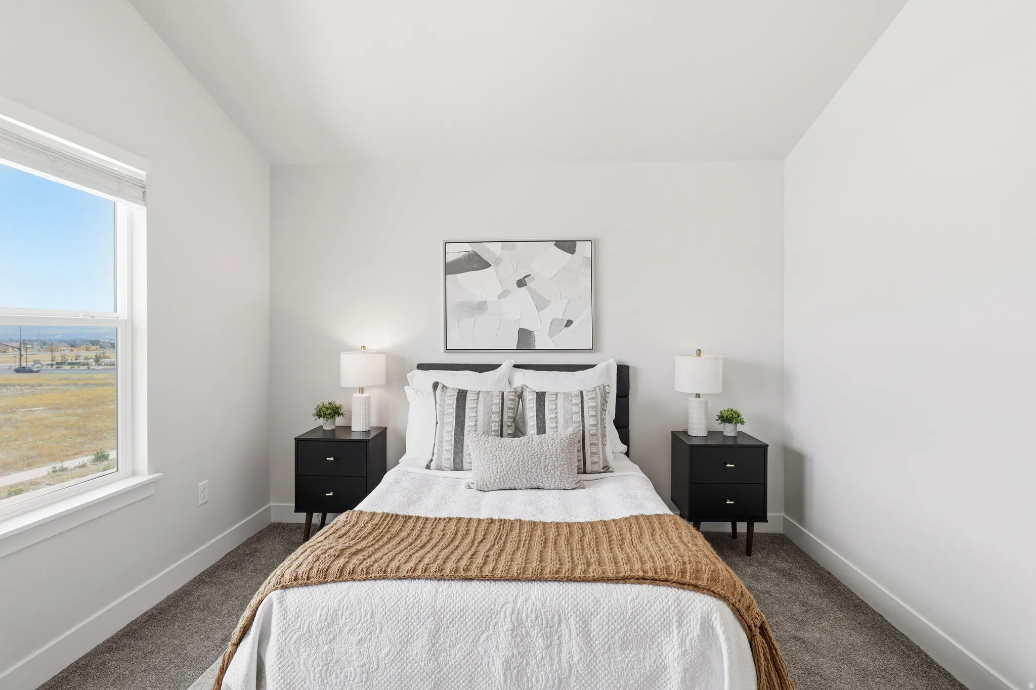 Bright interior with a large window, soft gray carpet, and white baseboards