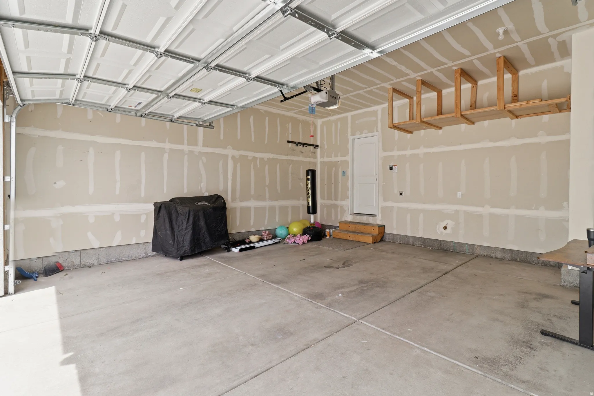 Spacious garage featuring a concrete floor, overhead door, and built-in ceiling storage racks