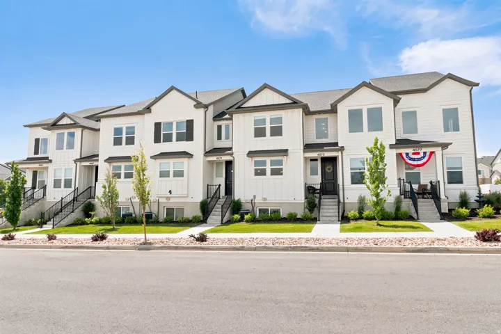 Contemporary townhome row featuring white siding with dark gray trim and gabled rooflines