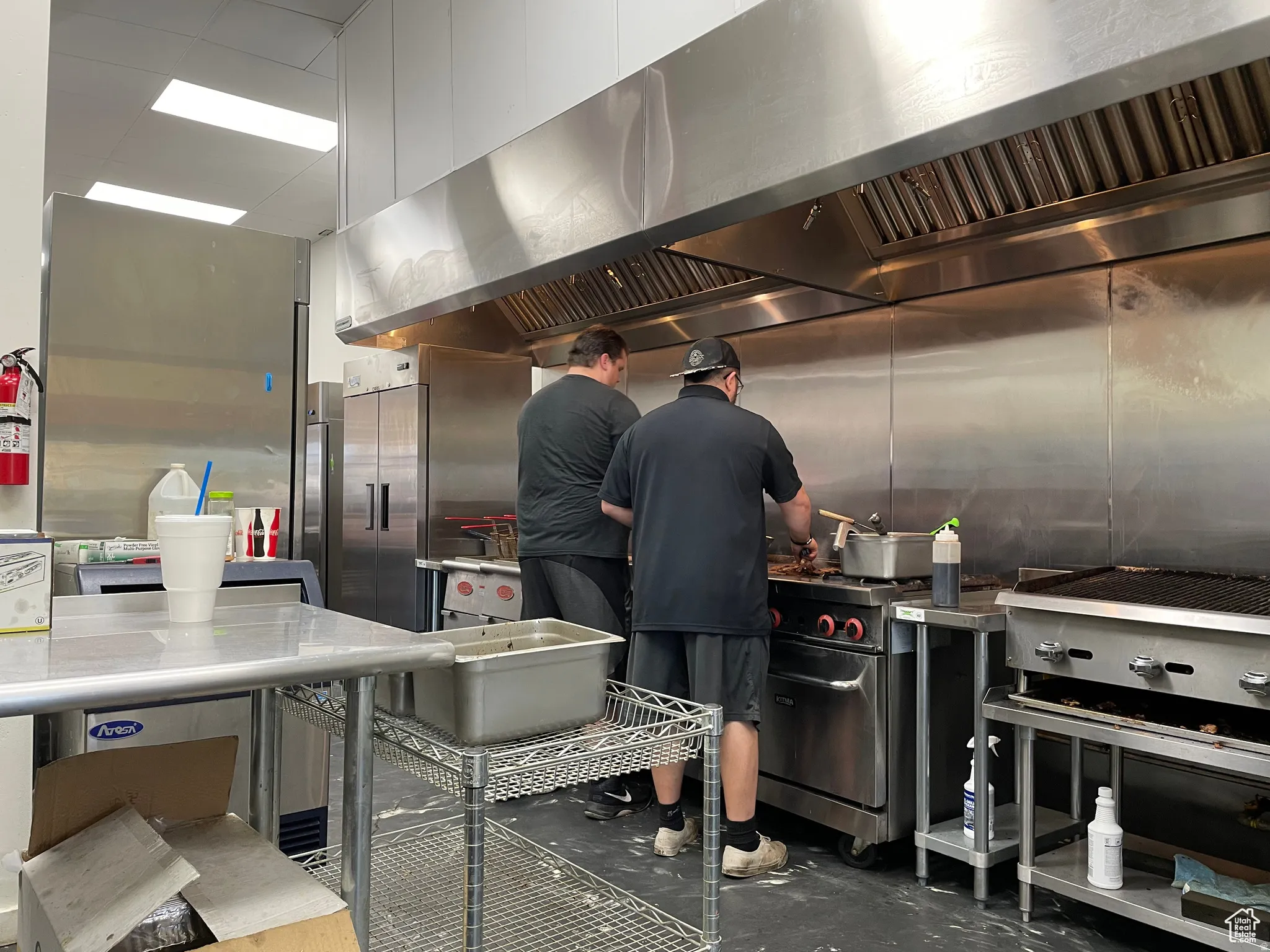 Commercial kitchen featuring stainless steel appliances, large ventilation hood, and extensive counter space