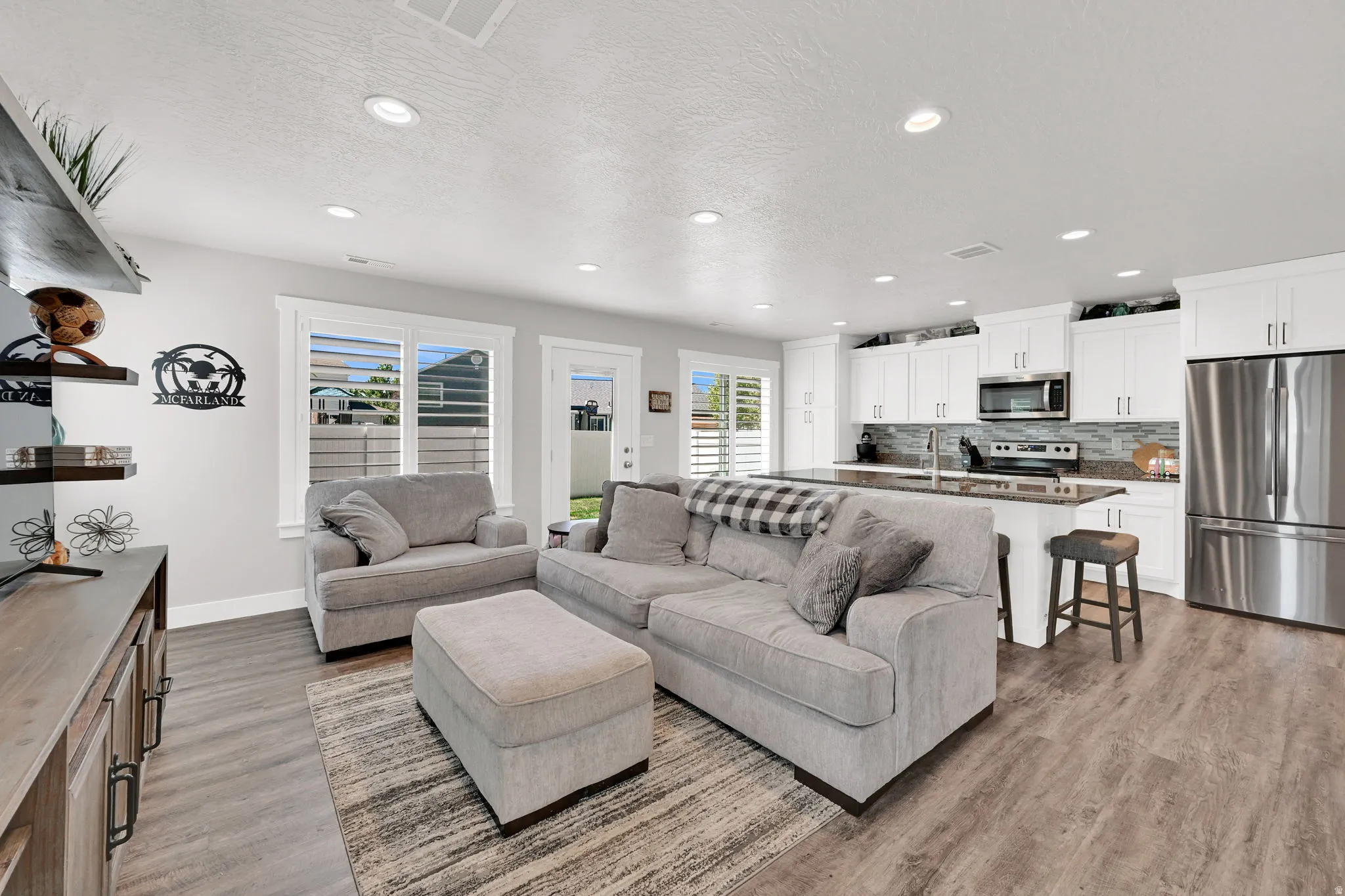 Open-concept living space/kitchen  featuring LVP flooring, recessed lighting, and white plantation shutters