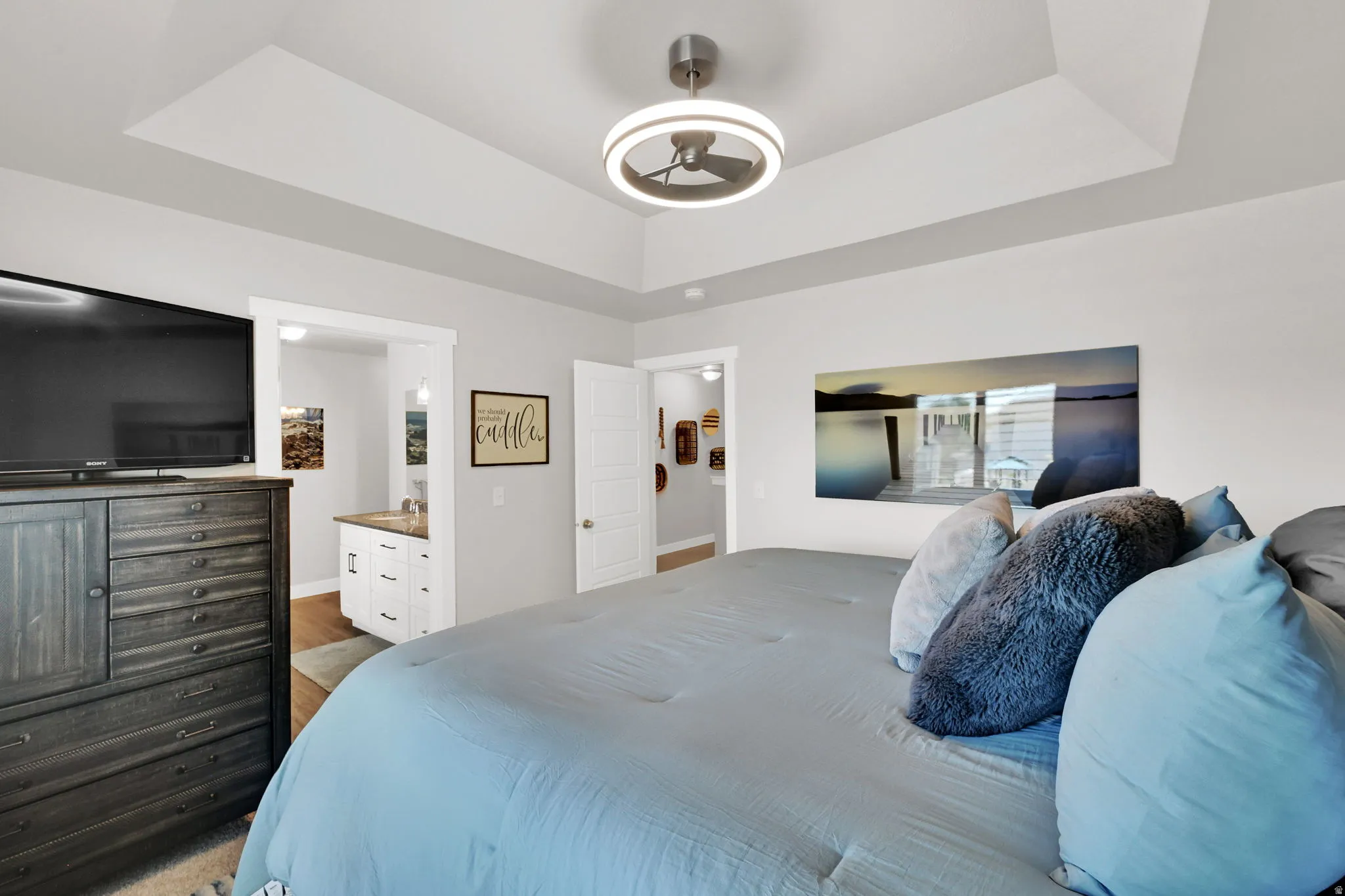 Primary Bedroom- featuring primary en suite, walk in closet, window with plantation shutters, ceiling fan with integrated lighting, carpet, and light-toned wall paint