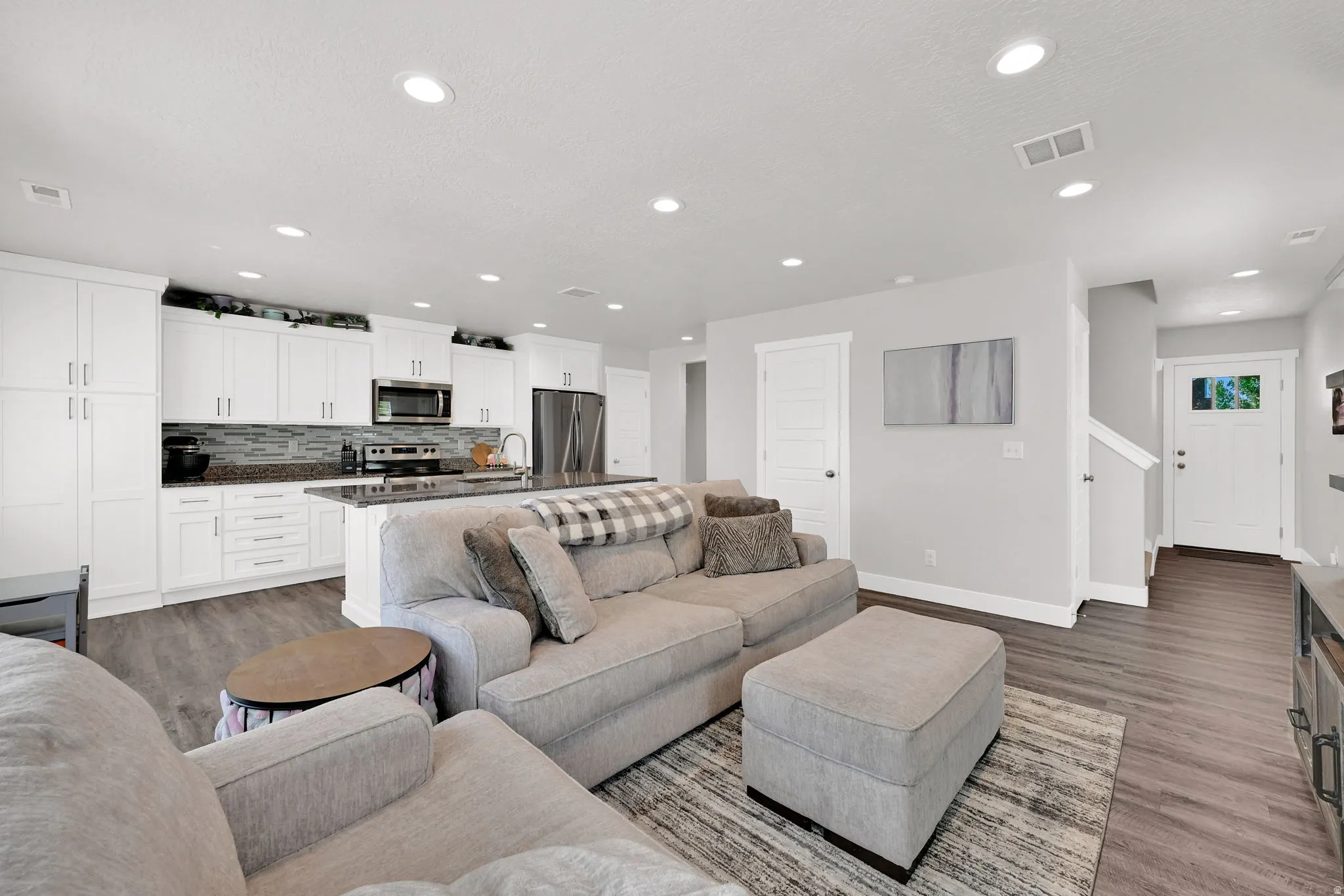 Open-concept living space/kitchen  featuring LVP flooring, recessed lighting, and white plantation shutters