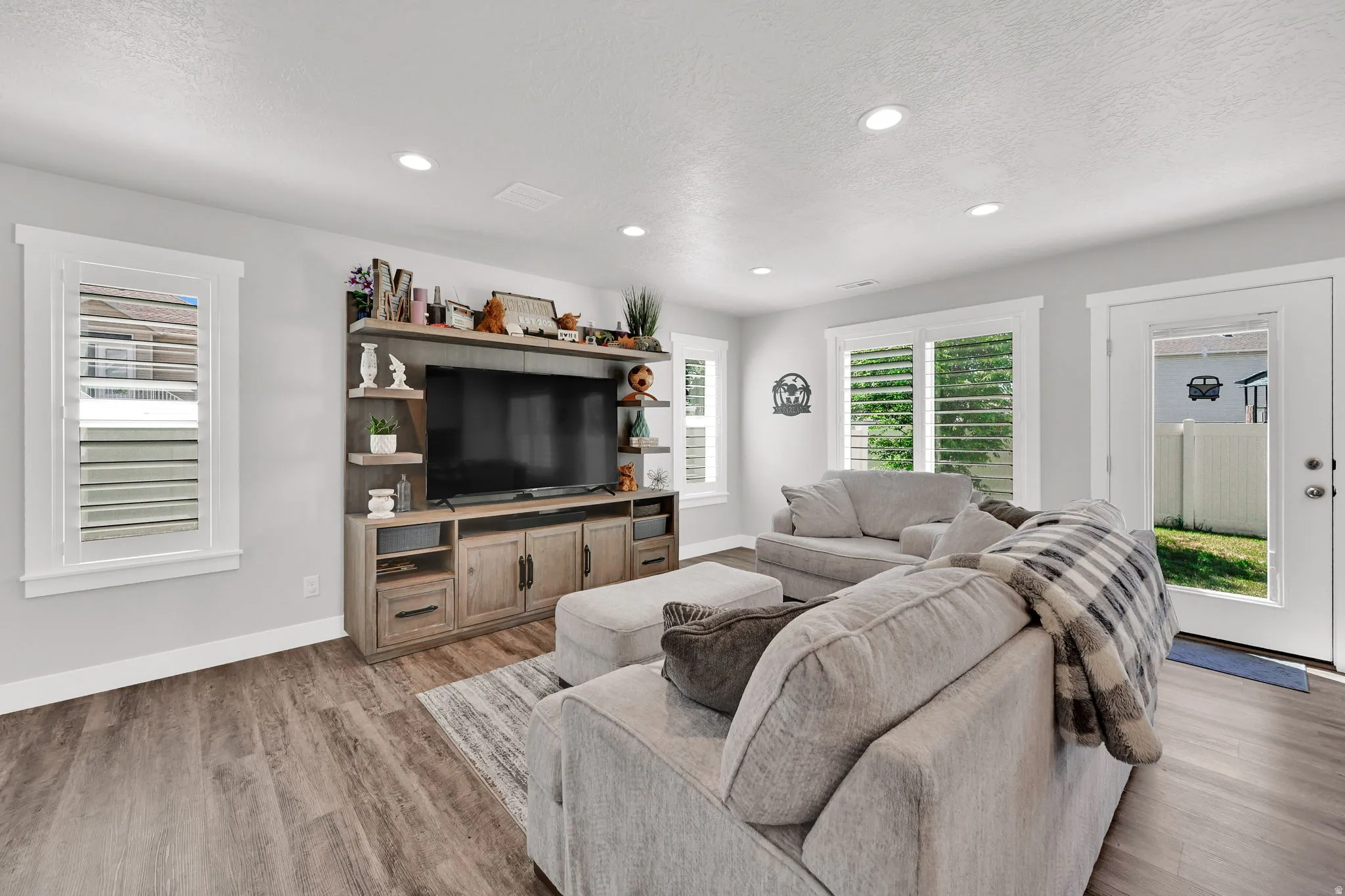 Open-concept living space/kitchen  featuring LVP flooring, recessed lighting, and white plantation shutters