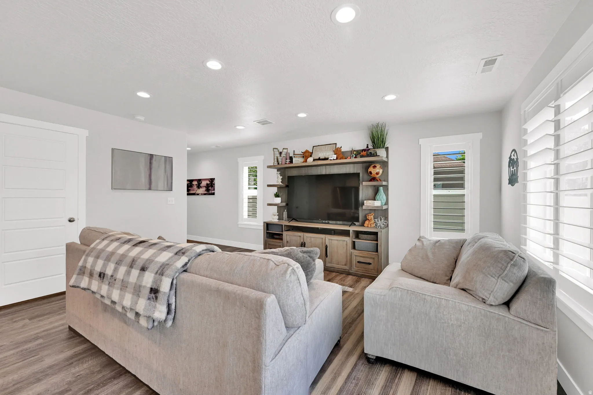 Open-concept living space/kitchen  featuring LVP flooring, recessed lighting, and white plantation shutters
