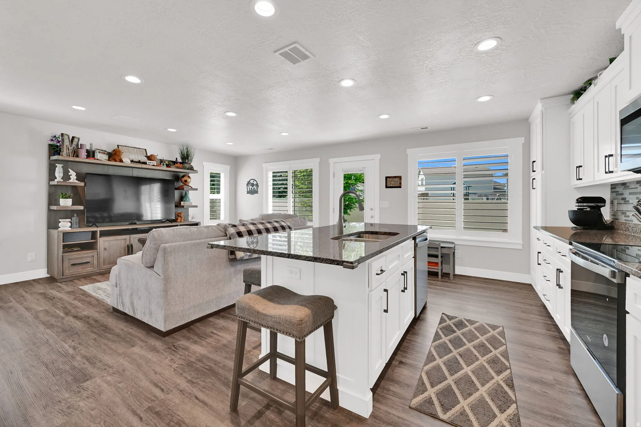 Open-concept living space/kitchen  featuring LVP flooring, recessed lighting, and white plantation shutters