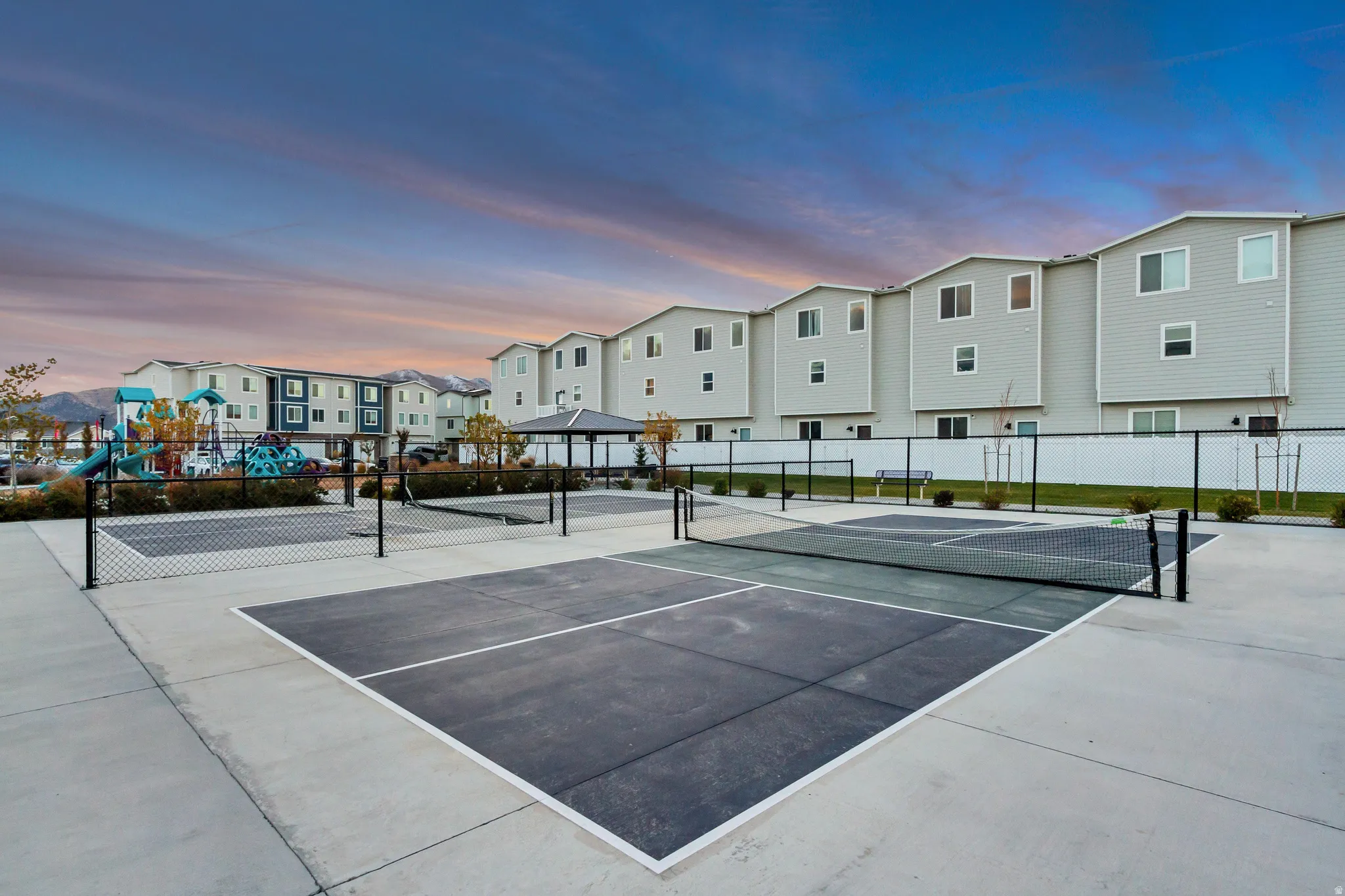Community recreational courts featuring two pickleball courts with concrete surfacing and black netting
