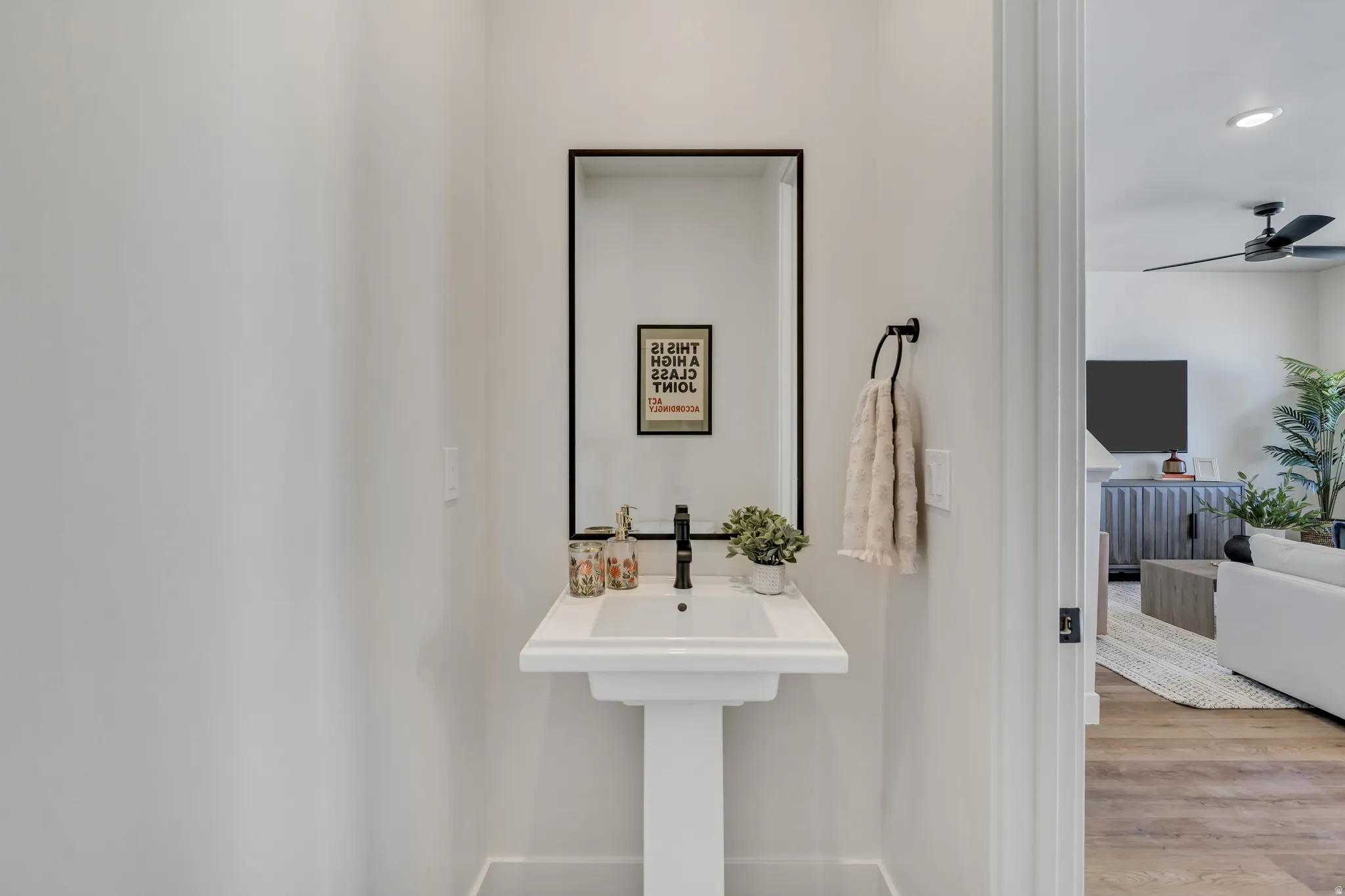 Pedestal sink with black matte faucet and framed mirror