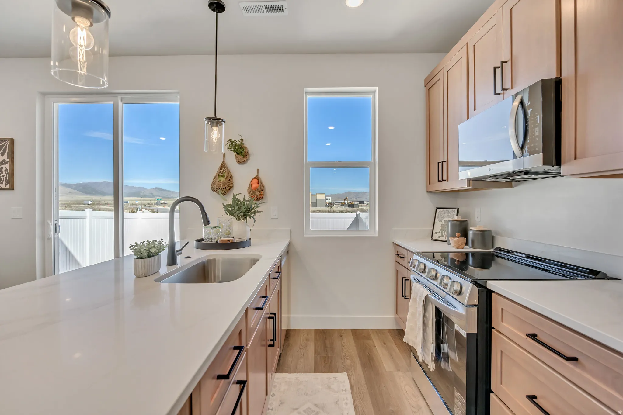 Modern kitchen featuring light wood-finish cabinetry with black hardware, white countertops, and wood-finish flooring