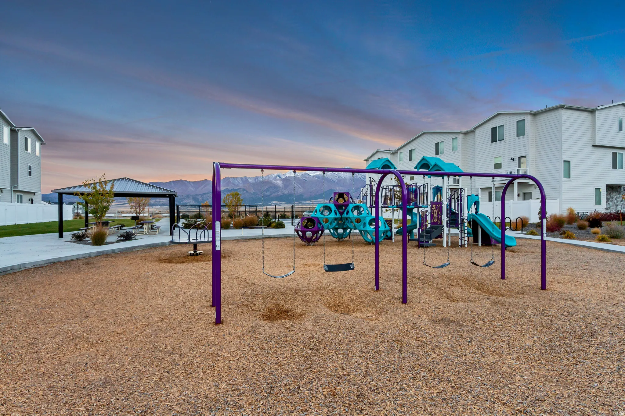 Community playground featuring swings, multi-level play structures, and a dedicated picnic area with a covered gazebo