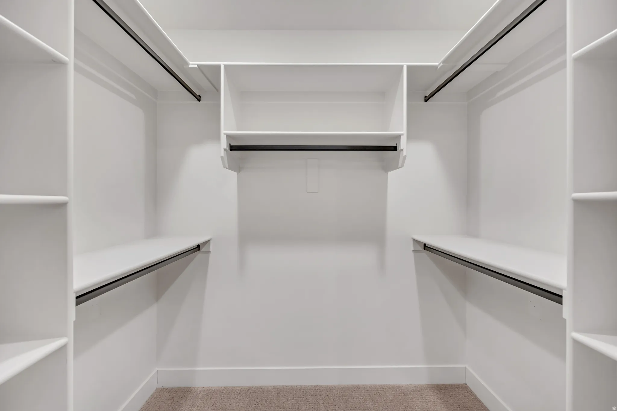 Walk-in closet featuring built-in shelving, multiple hanging rods, and neutral-toned carpeting