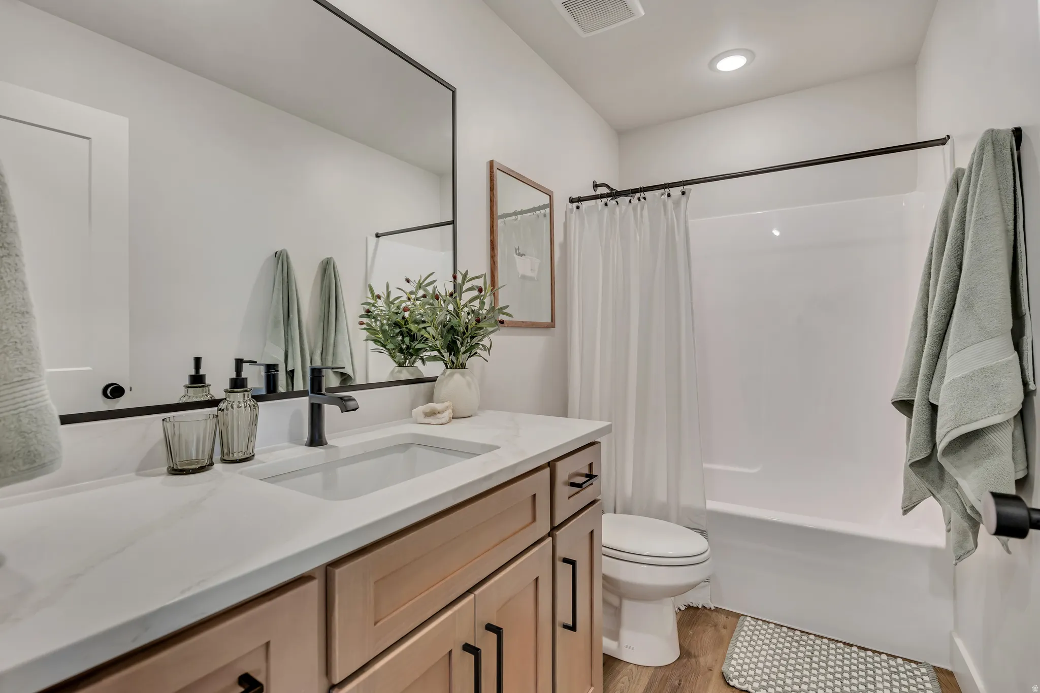 Bathroom featuring a single vanity with wood-finish cabinetry, a white countertop, and an integrated rectangular sink