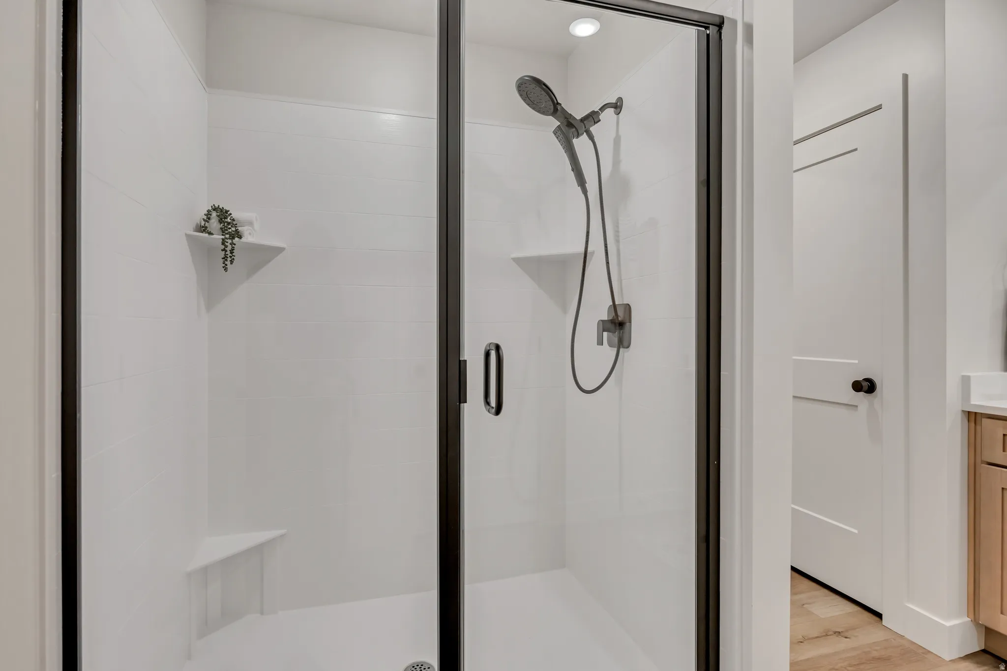 Walk-in shower featuring a frameless glass enclosure with matte black trim, white subway tile surround, built-in corner bench, and dual shower heads
