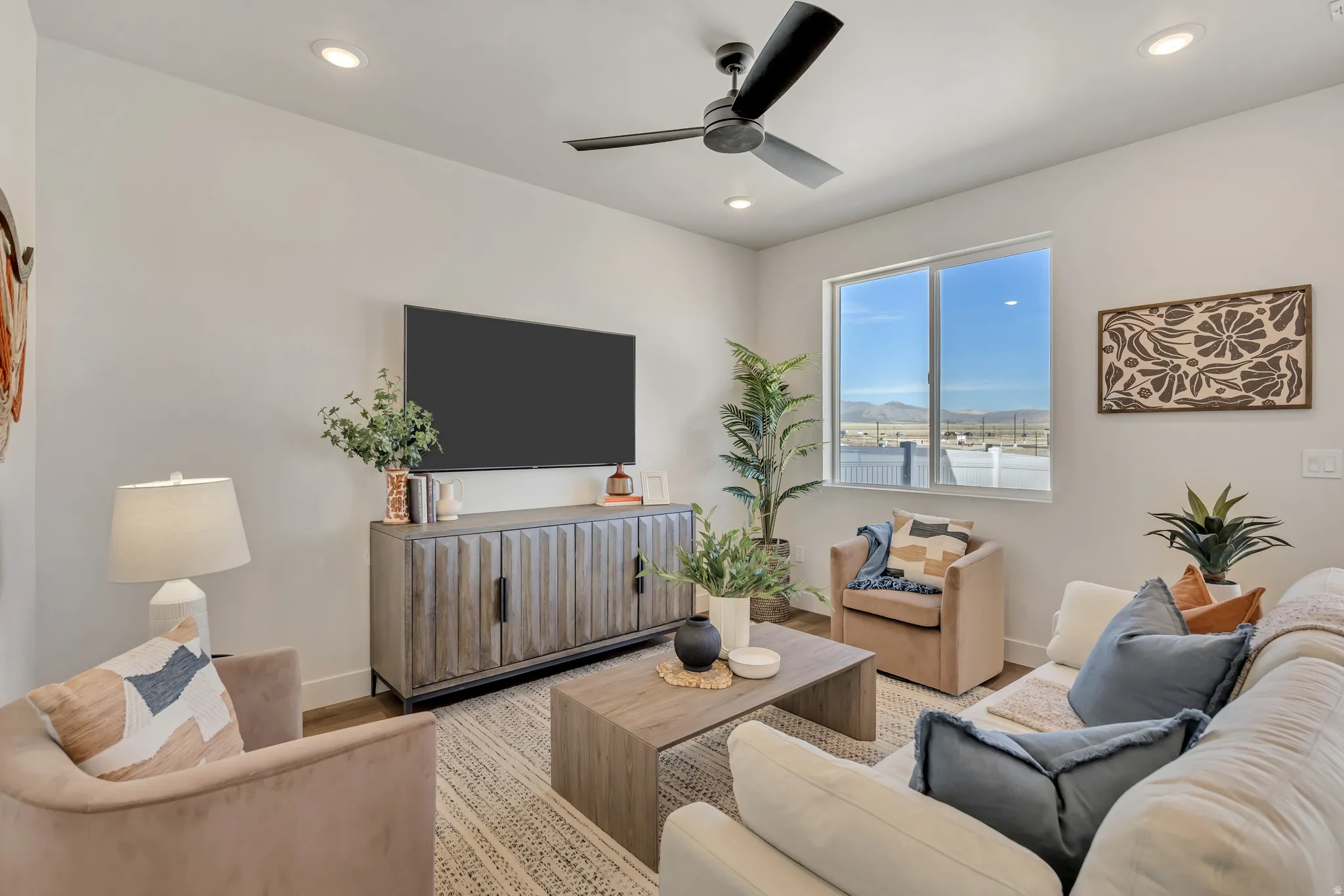 Bright living space featuring a modern ceiling fan with integrated lighting, recessed ceiling lights, and wood-finish flooring
