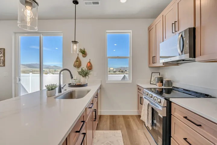 Modern kitchen featuring light wood-finish cabinetry with black hardware, white countertops, and wood-finish flooring